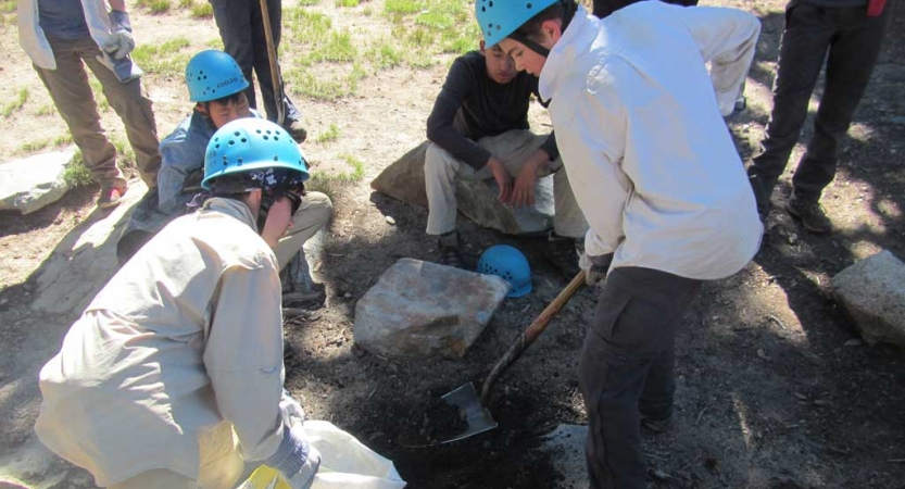 A group of students wearing helmets use tools during a service project. 